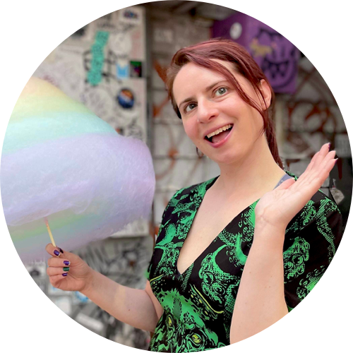 Jess Luszcz holding rainbow cotton candy in front of a graffiti wall